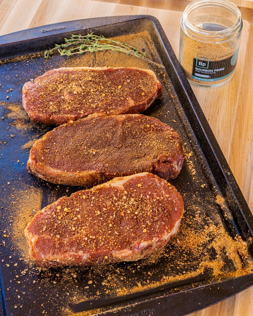 NY Strip Steaks with Gorgonzola Mushroom Cream Sauce getting seasoned