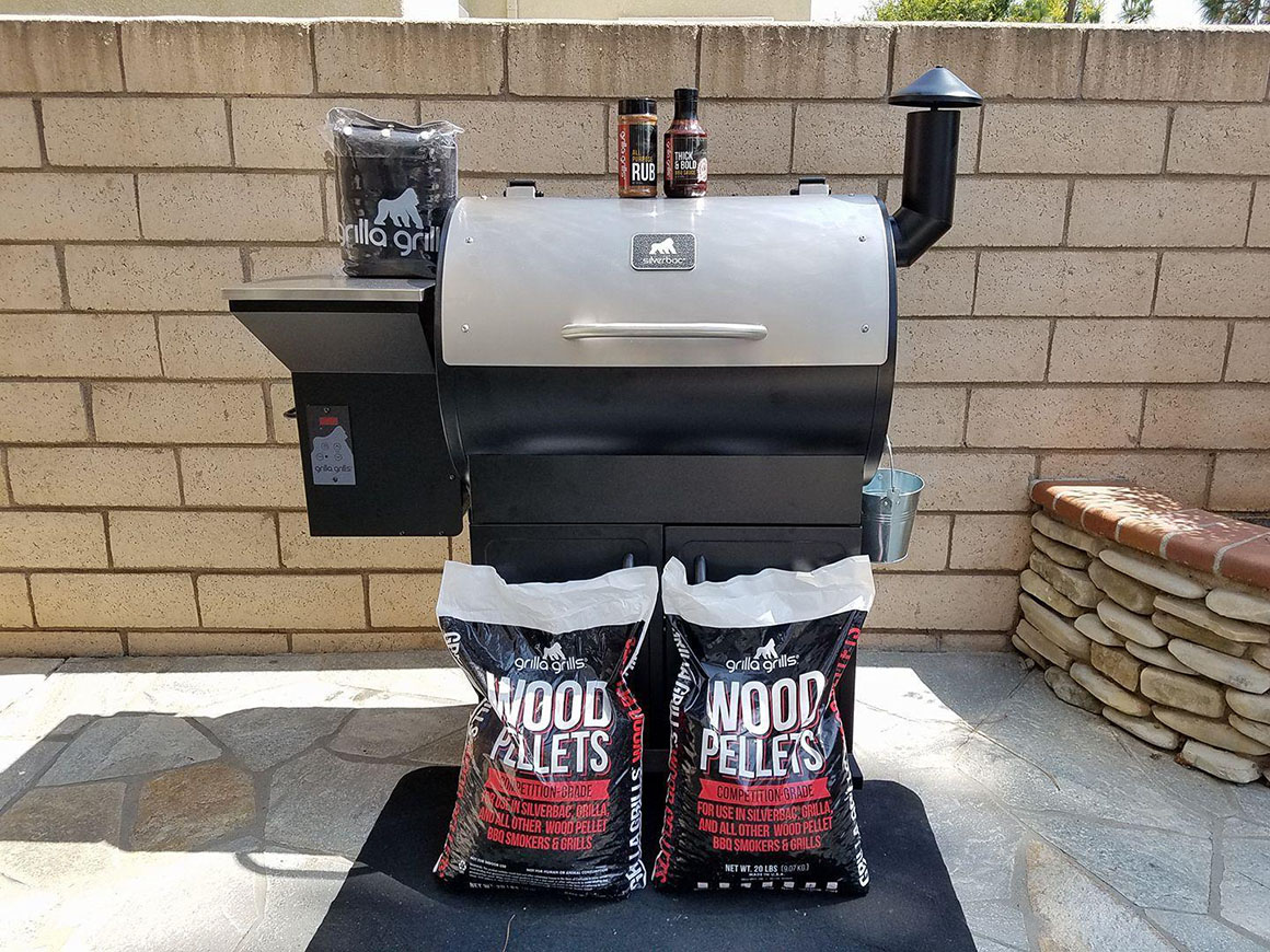 a pellet smoker with two bags of wood pellets in front of it