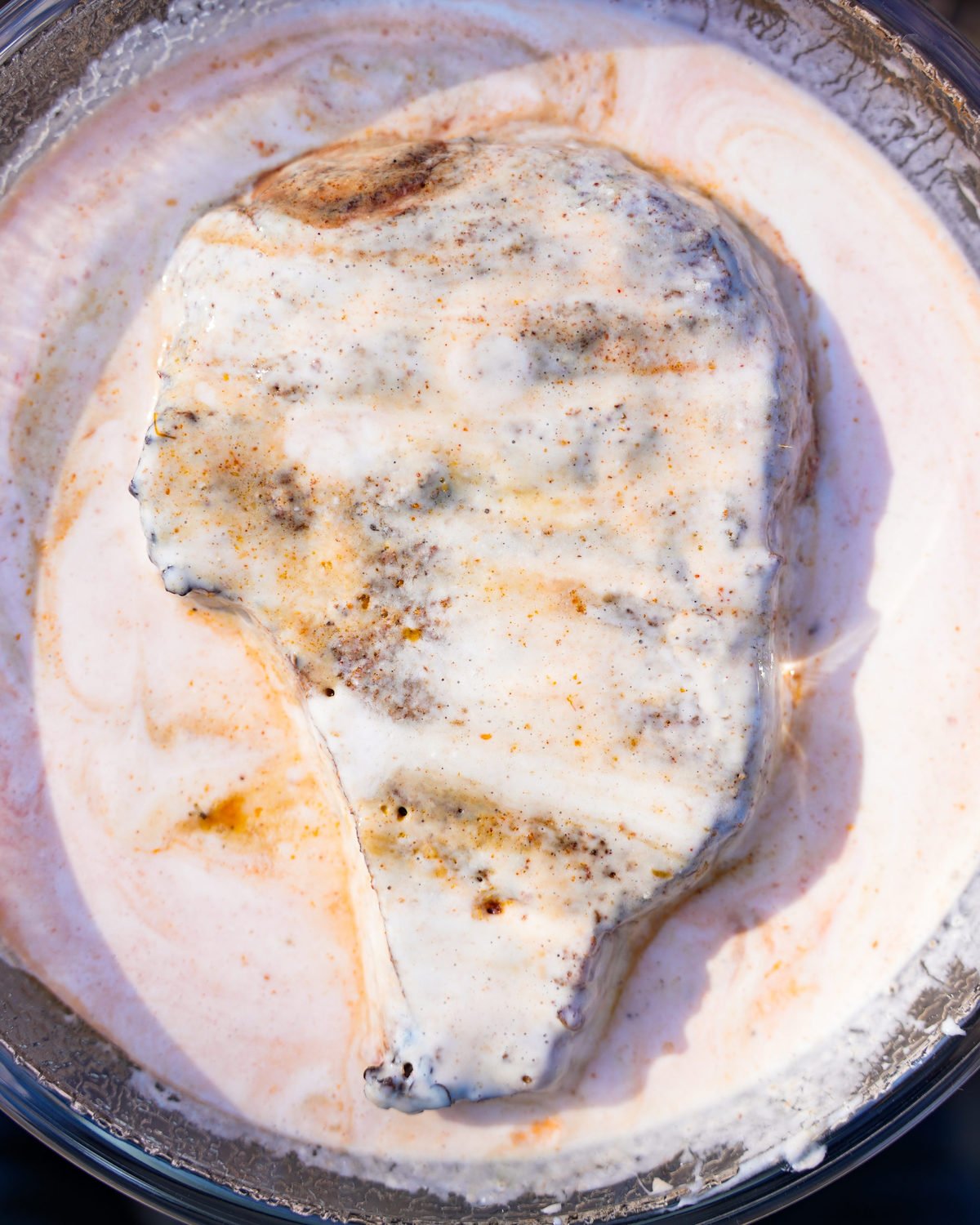 Dipping the ribeye in buttermilk and hot sauce. 