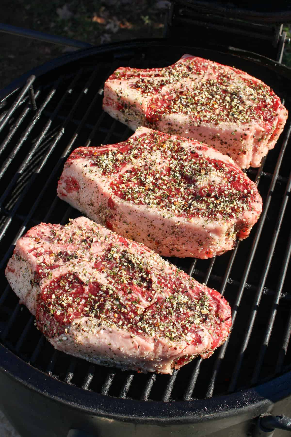 Seasoned steaks on the smoker.