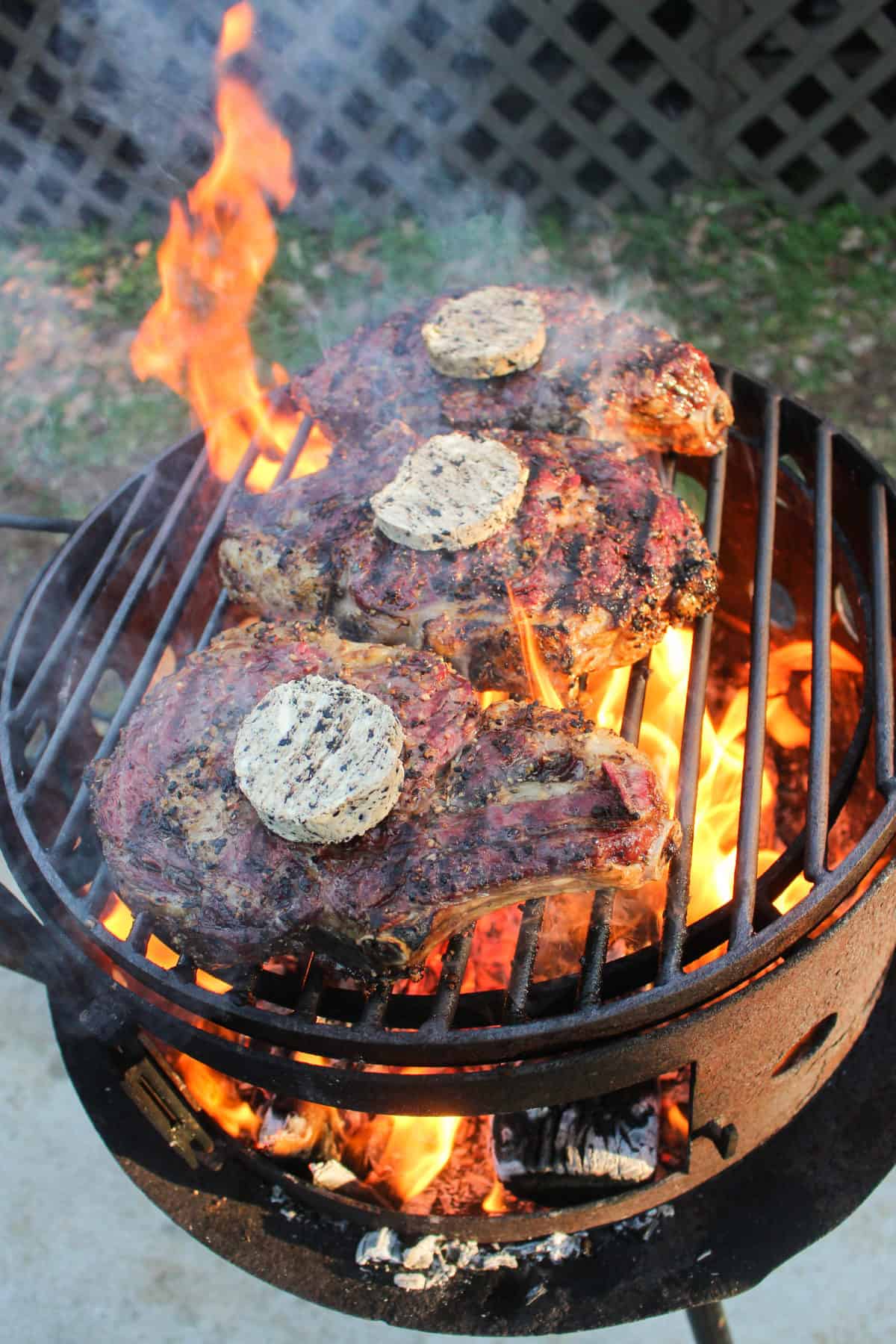 Reverse Seared Ribeyes being topped with Black Garlic Butter.