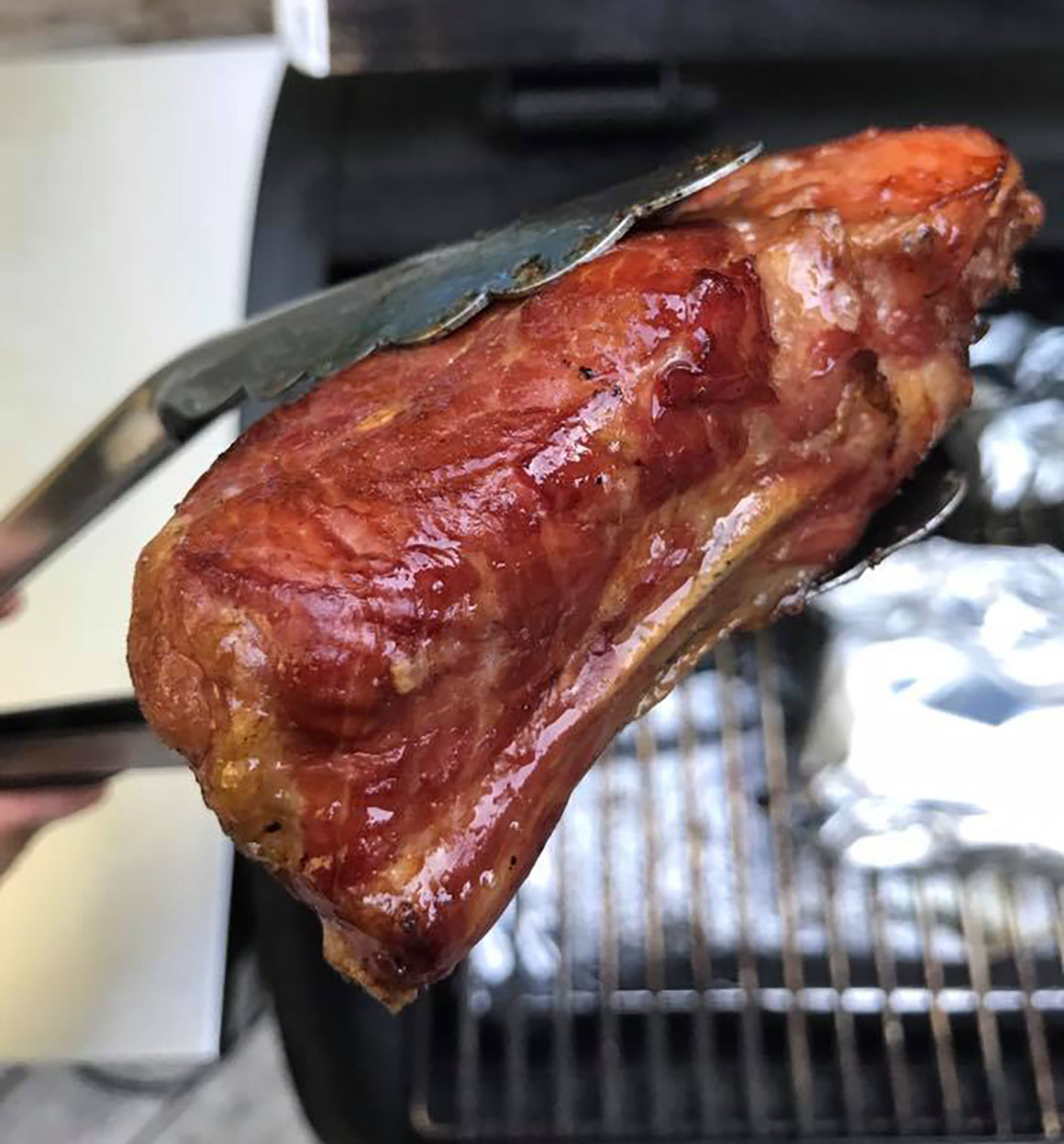 meat in tongs prepped for grilling