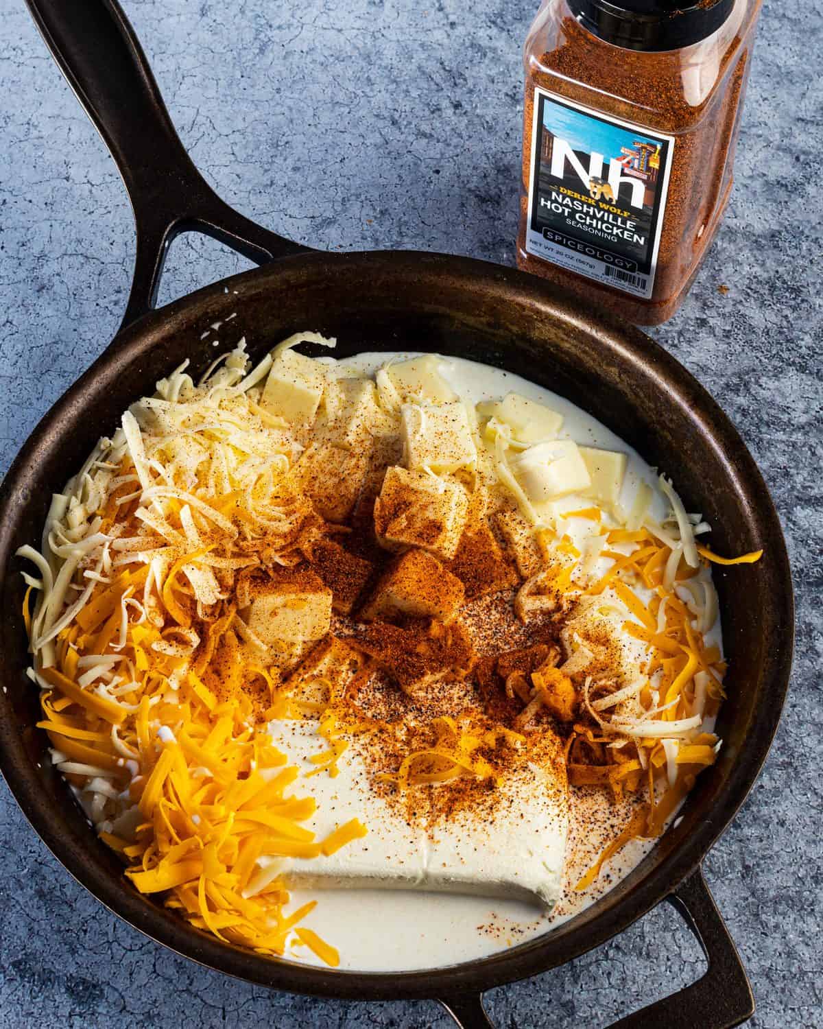 All the different cheeses in the skillet, ready to become Smoked Nashville Hot Chicken Queso.