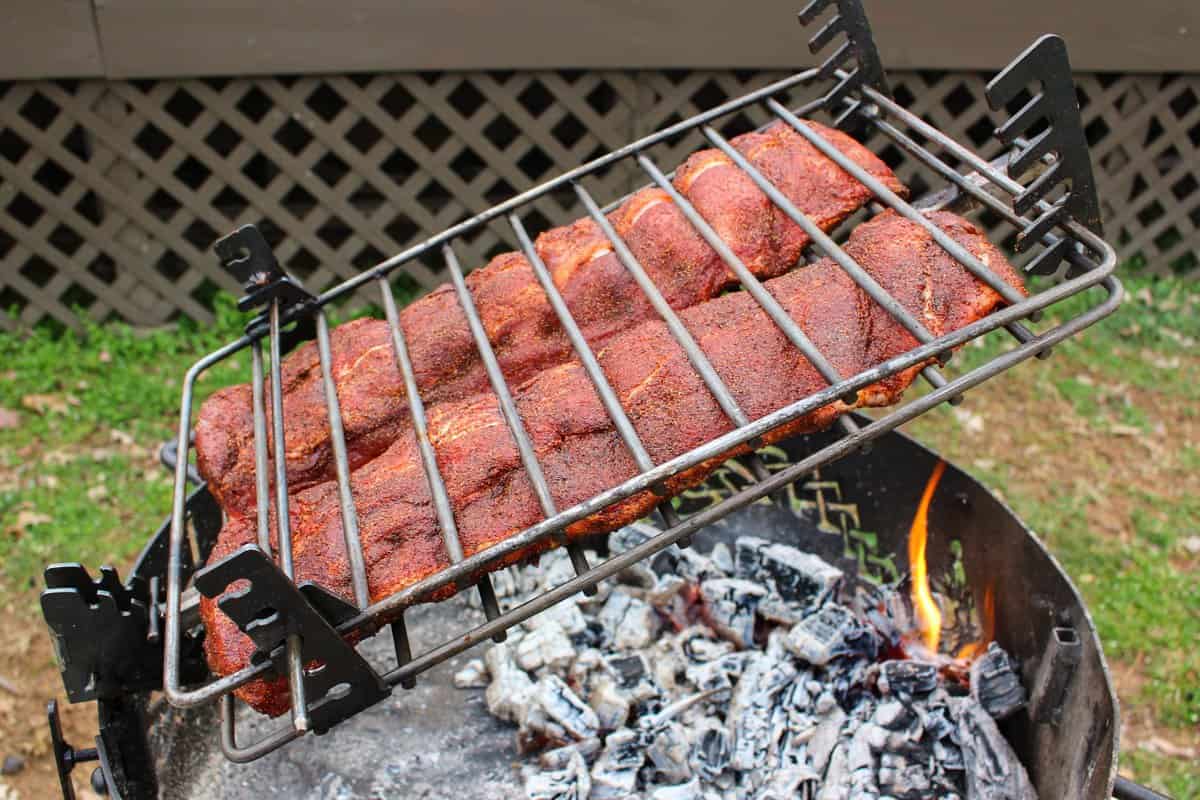 Huli Huli Ribs with Sriracha BBQ Sauce secured over the coals in a leaning basket.