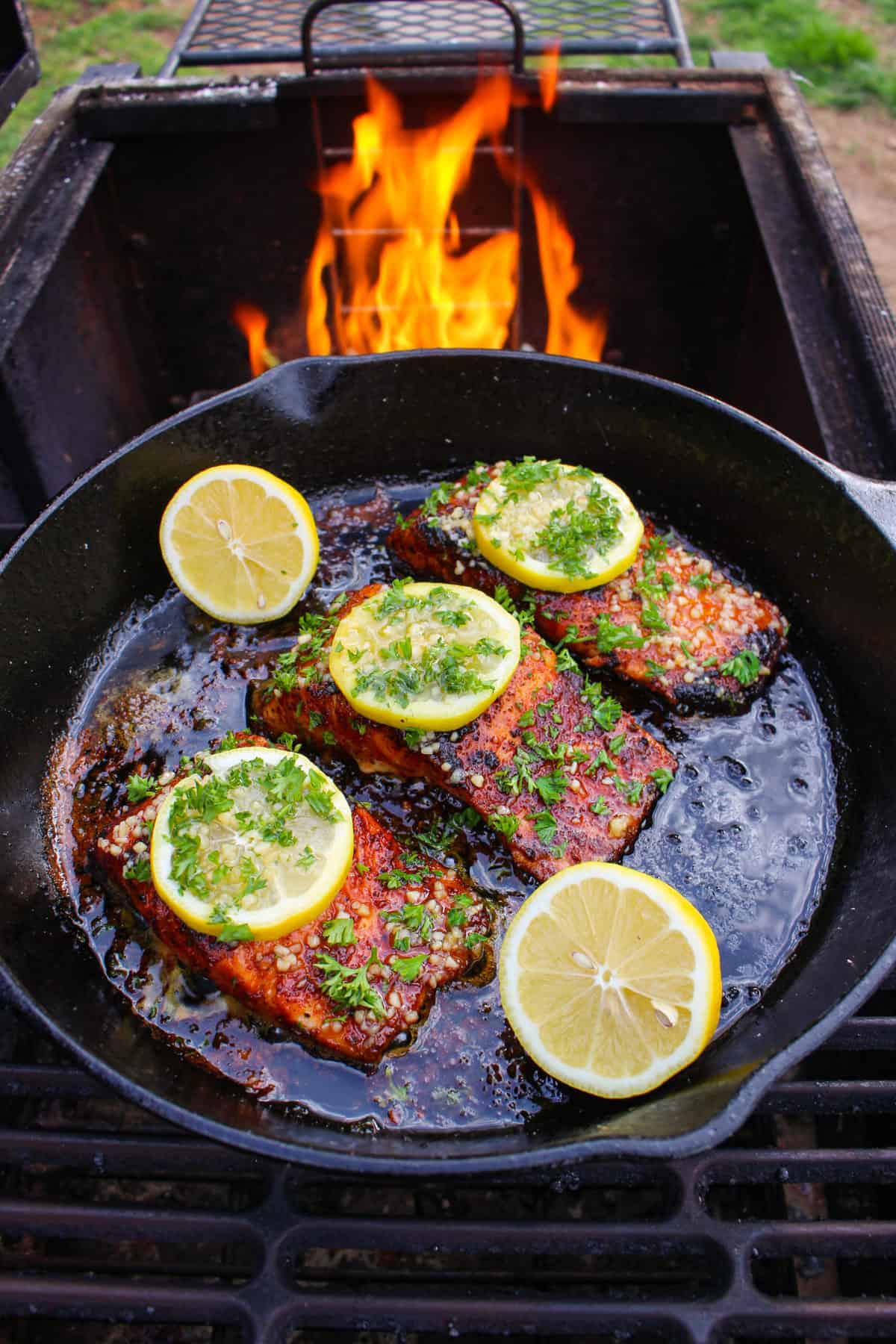 The salmon still on the grill being topped with the Honey Garlic Butter.