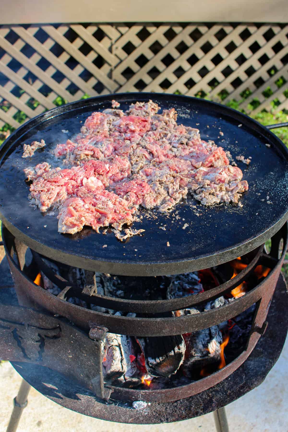 Steak hitting the plancha for the Smoked Cheesesteak Sliders.