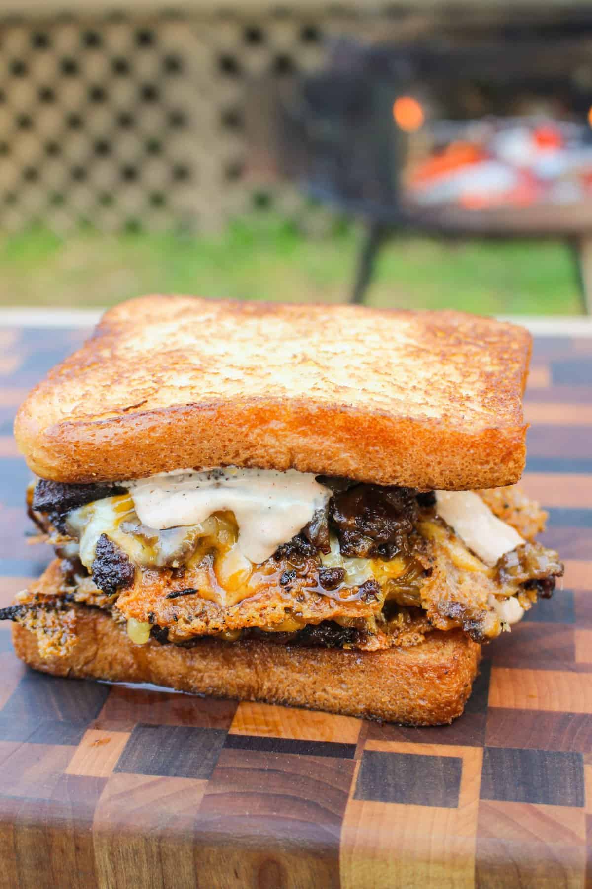 assembled burger sandwich on a cutting board from the side