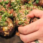 grilled steak pinwheel being lifted off of a cutting board with more pinwheels