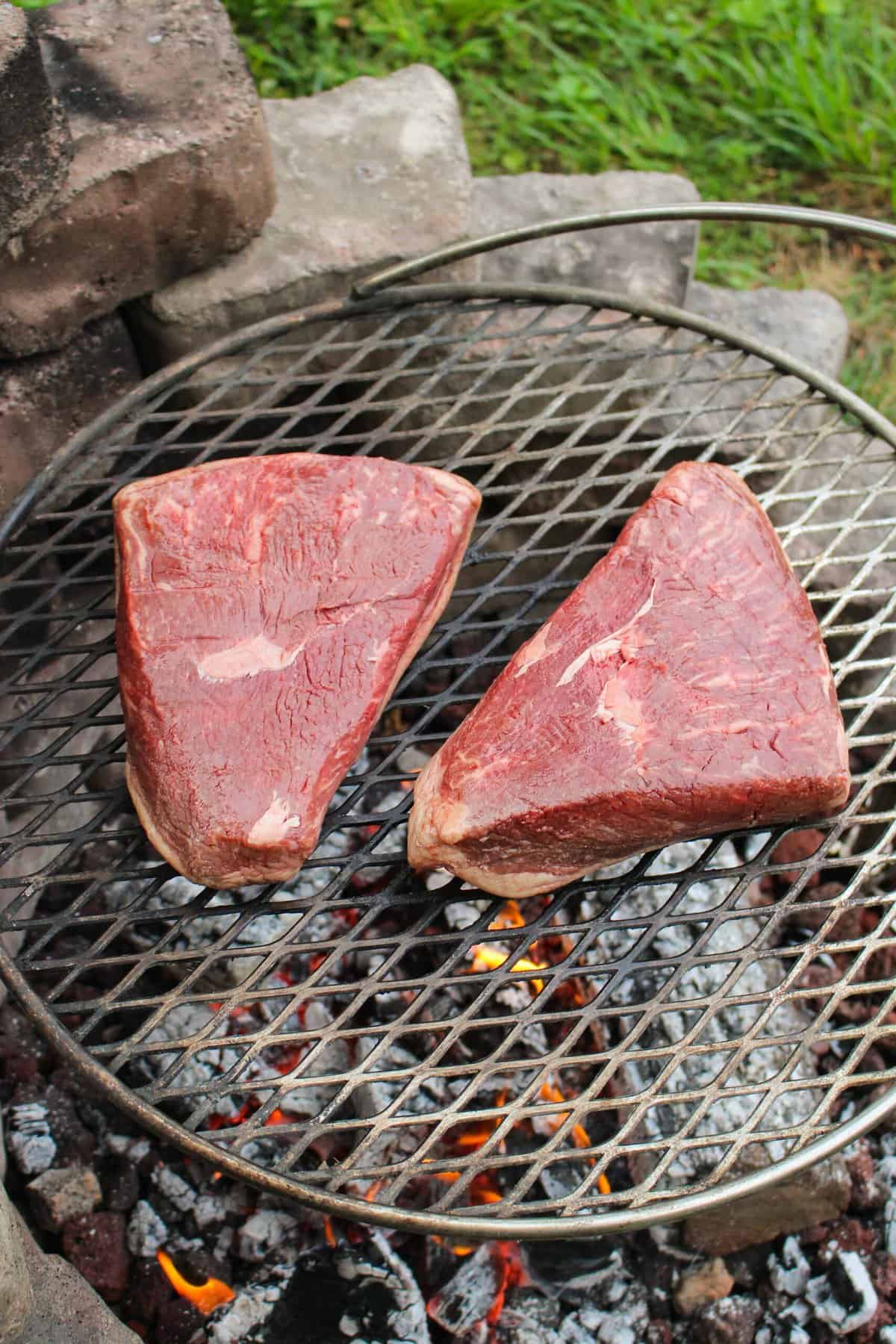 two pieces of steak on a grill grate overhead