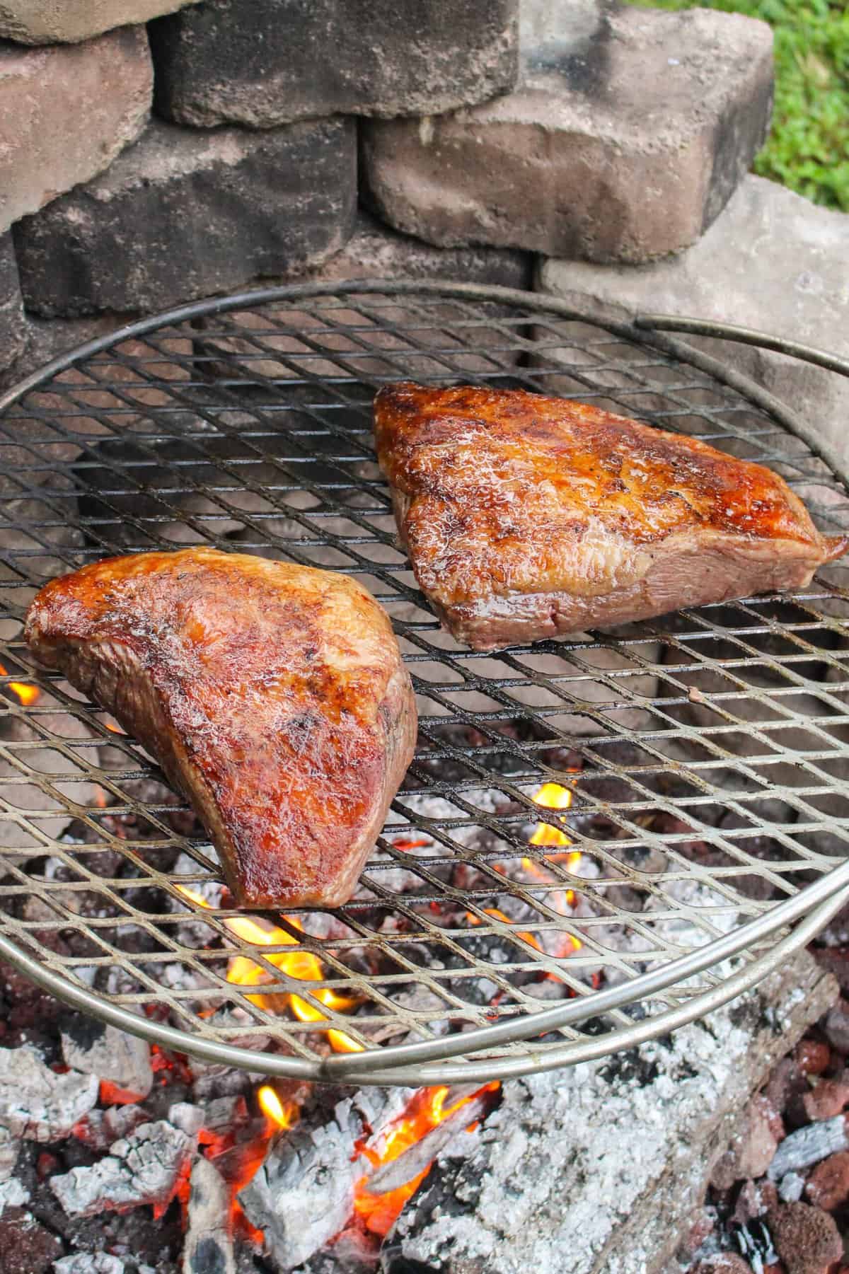 two grilled steaks on a grill grate