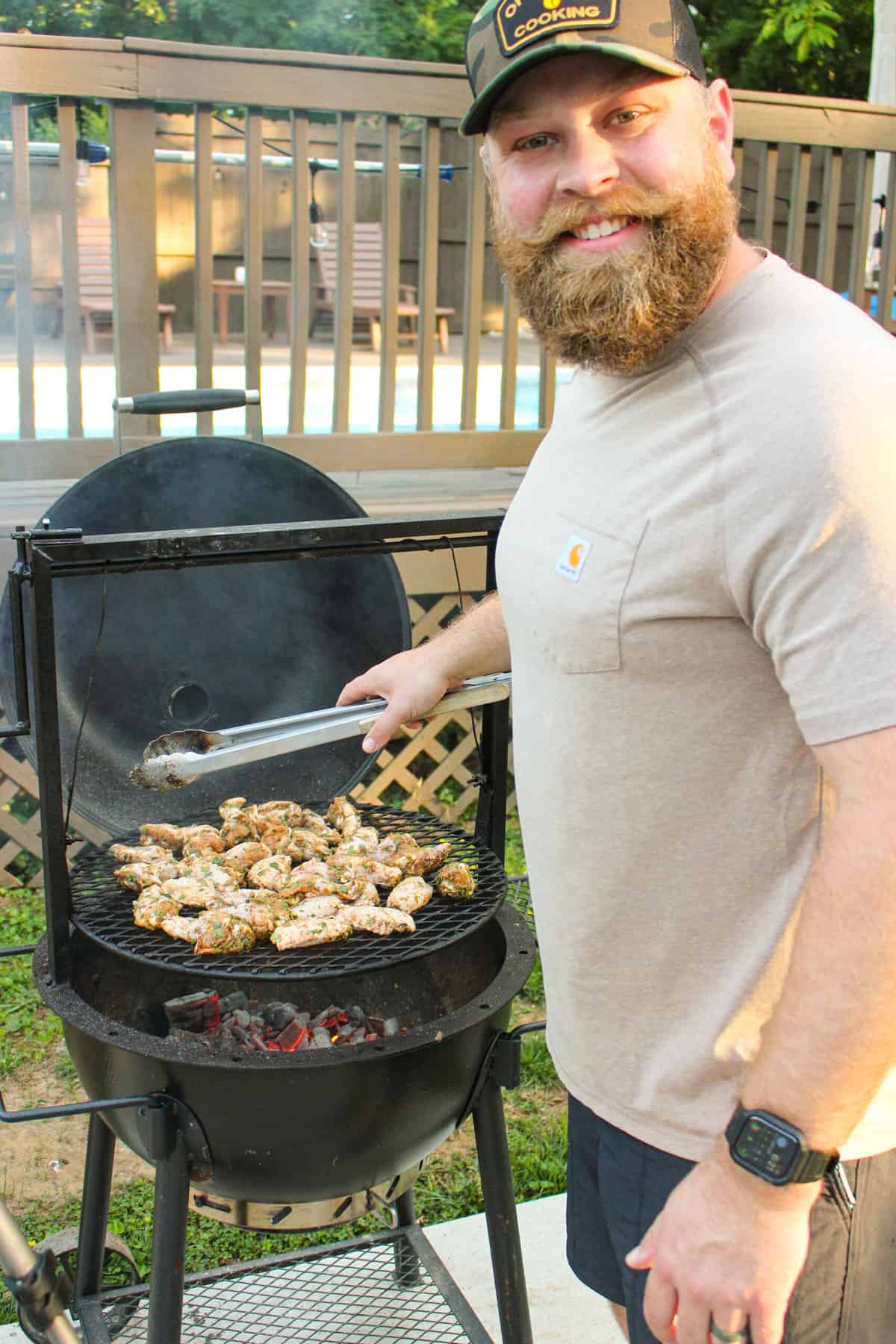 picture of a man at a grill cooking chicken wings