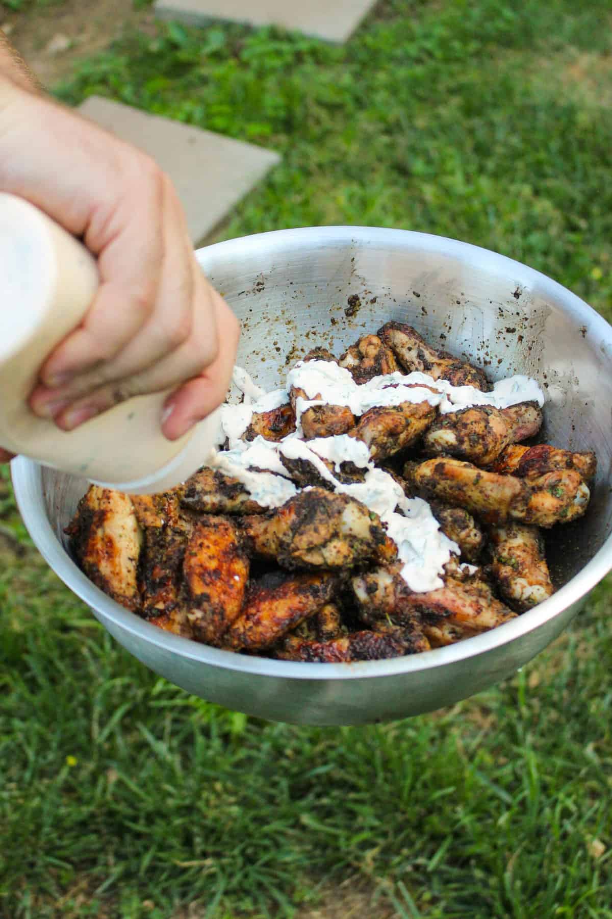 grilled chicken being drizzled with elote sauce