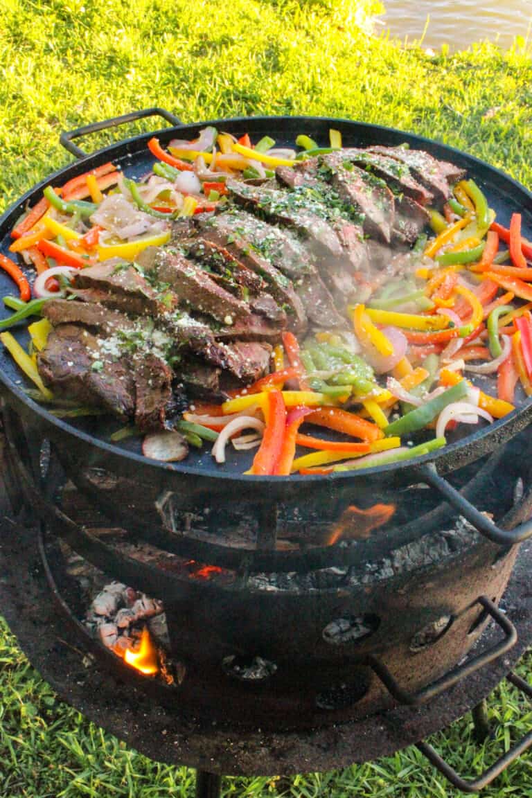 large plancha filled with fajita veggies and grilled steak