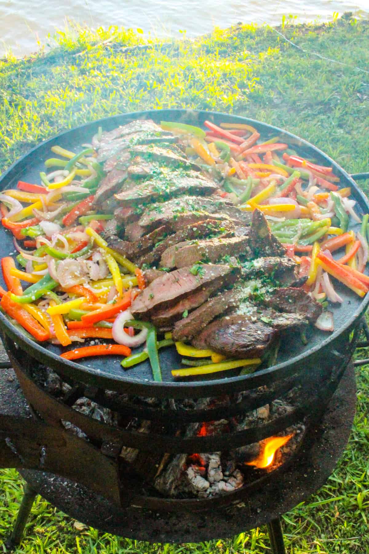 side view of steak and veggies for grilled flat iron fajitas on a large plancha