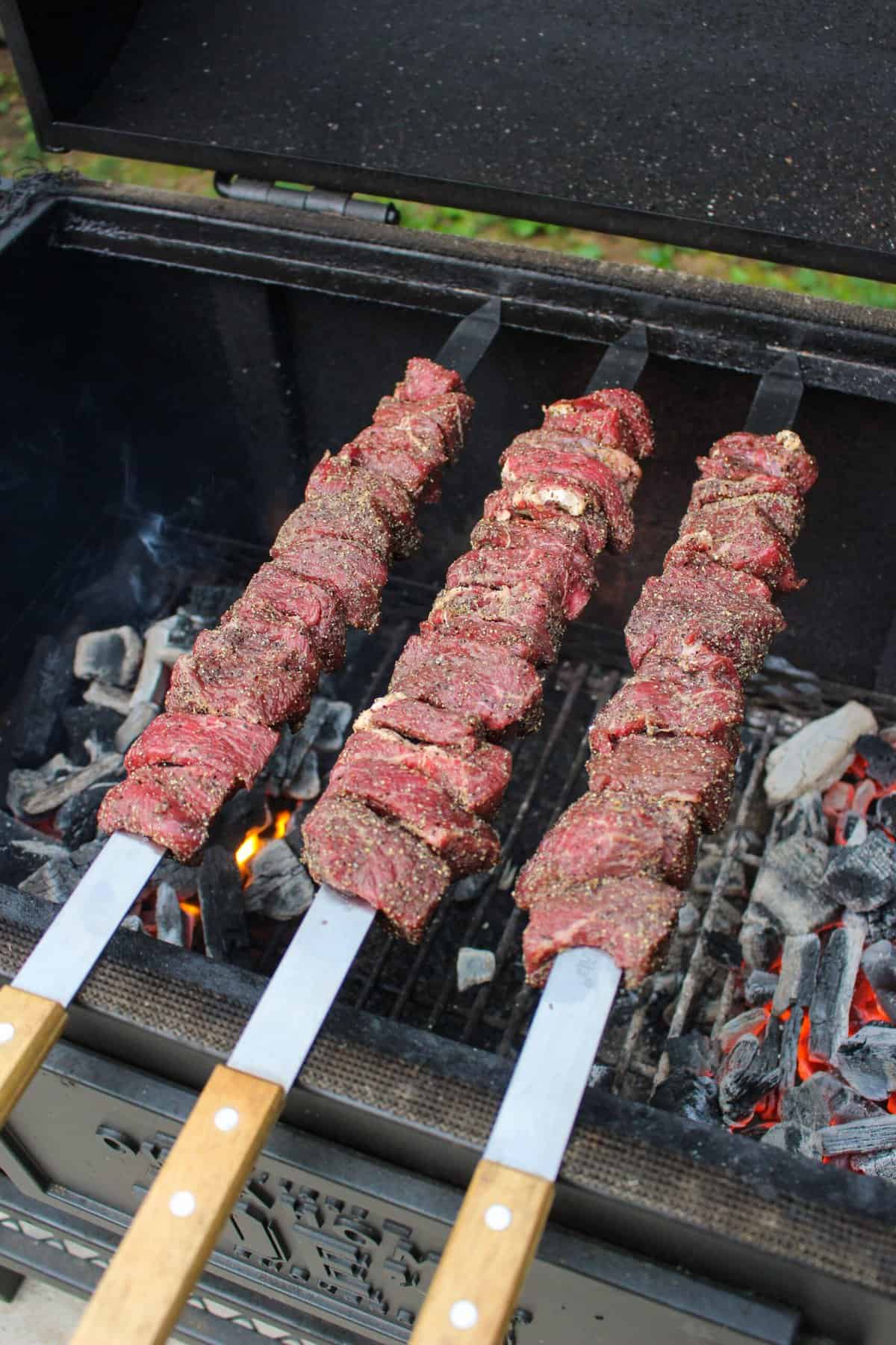 steak skewers added onto a grill overhead