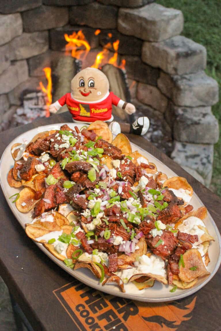 overhead of a plate of steak and blue cheese kettle chips next to a small Idaho potatoes doll