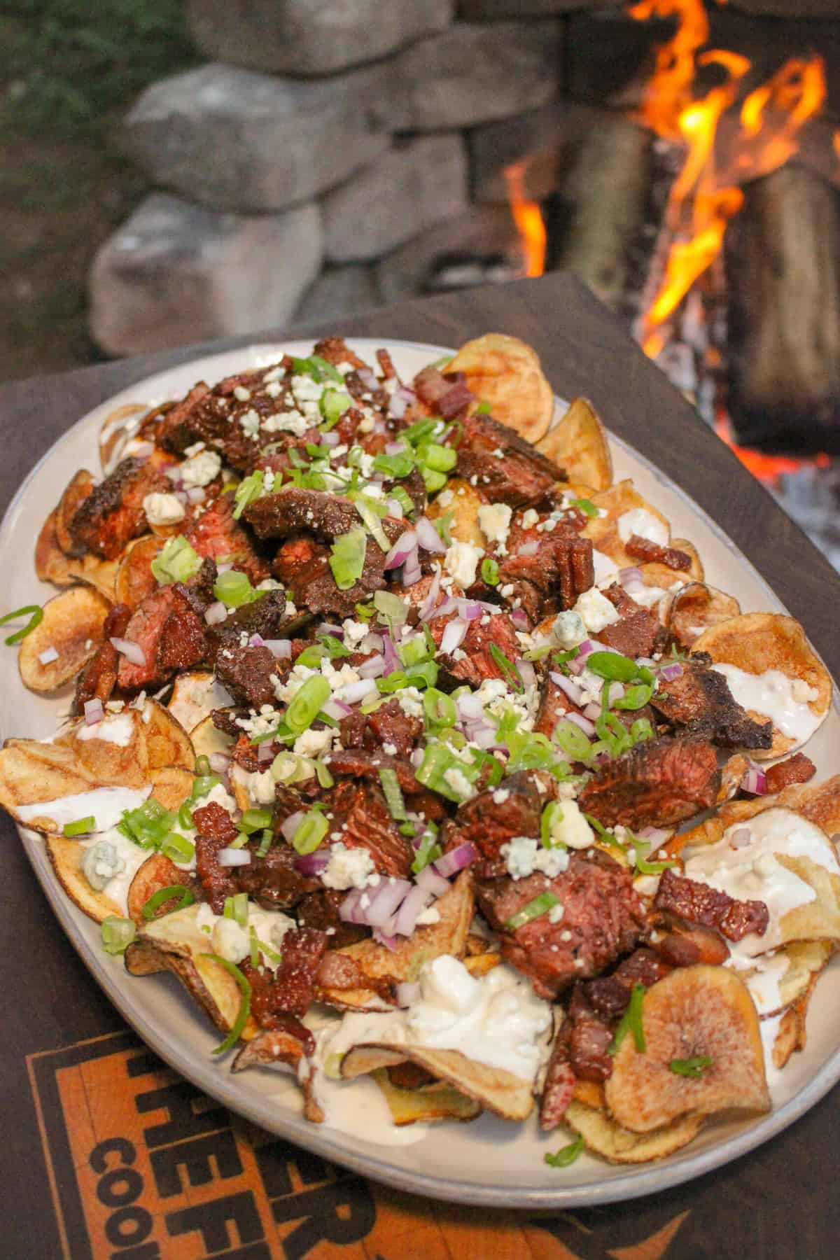 fully assemble steak and blue cheese kettle chips on a large platter next to a fire pit