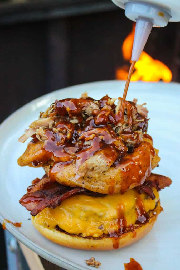 southwestern bbq burger being assembled on a plate and drizzled with bbq sauce