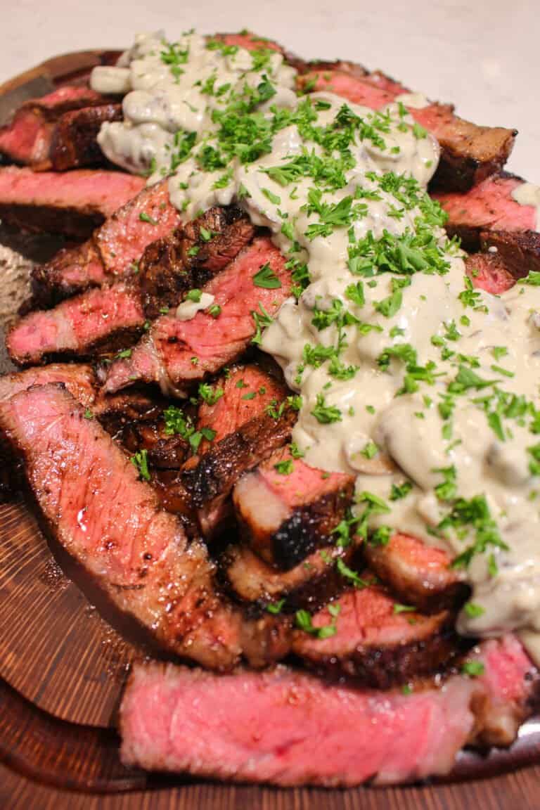 overhead of a pile of bourbon marinated ribeyes smothered in mushroom cream sauce