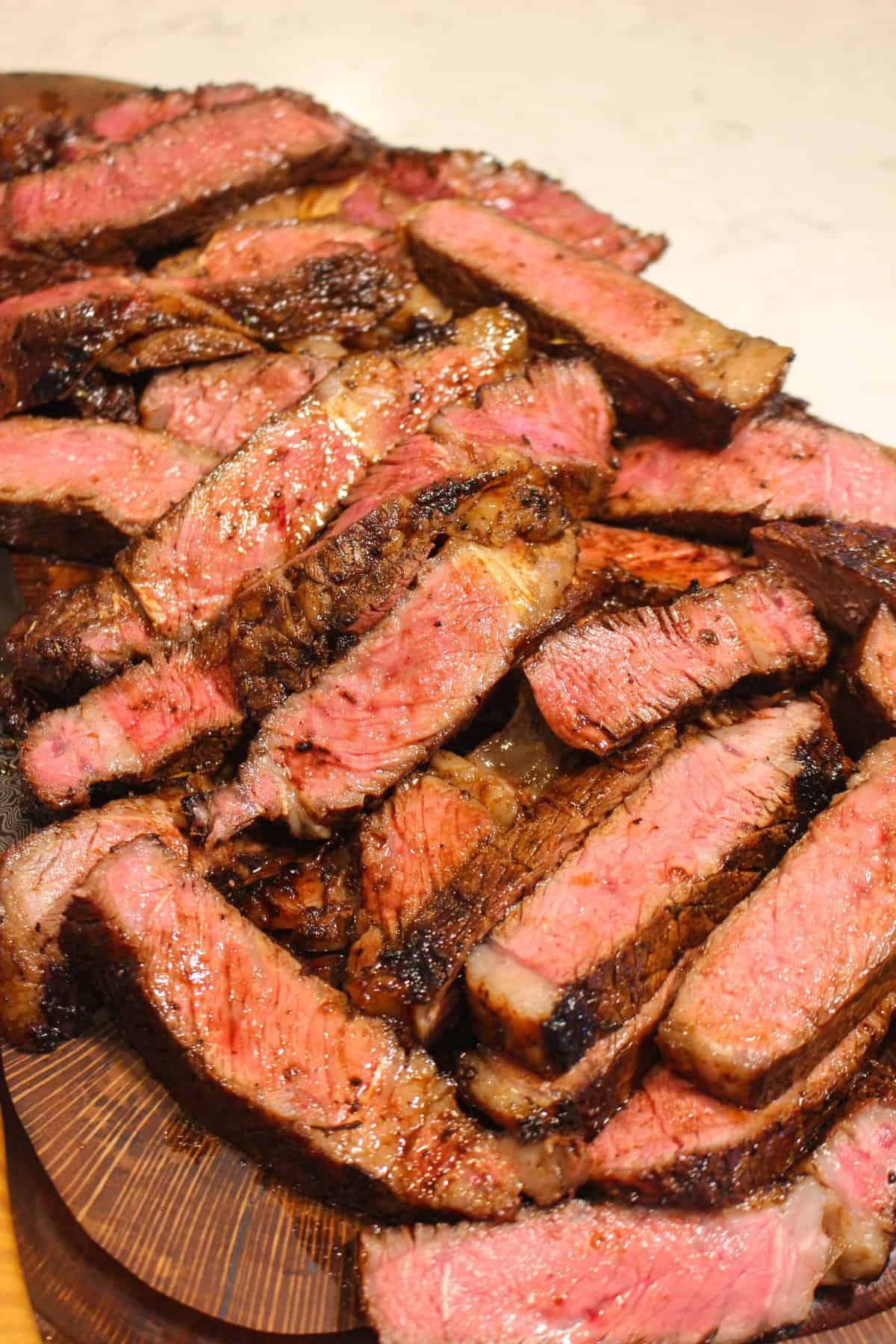 overhead of a pile of sliced steak on a cutting board