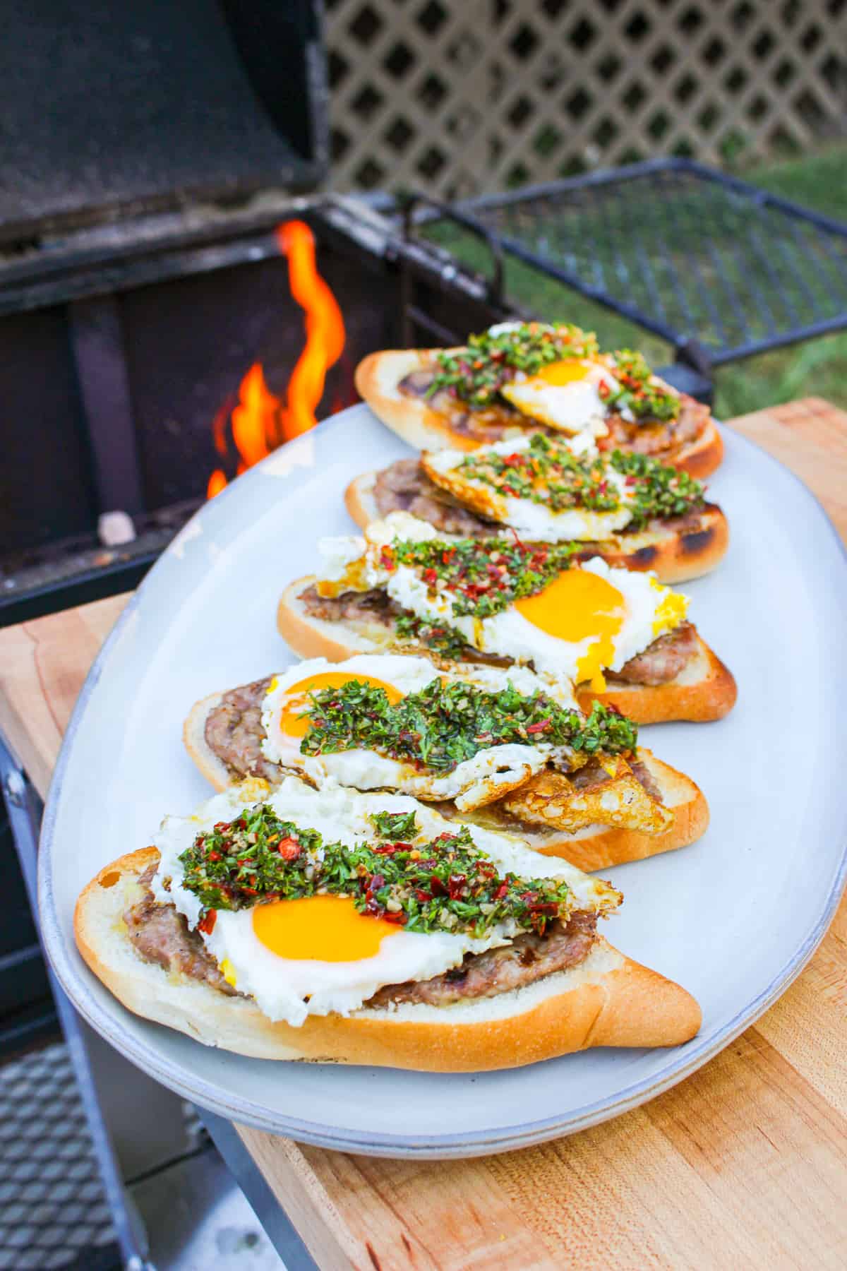 side view of buns layered with ground sausage, egg, and chimichurri on a plate