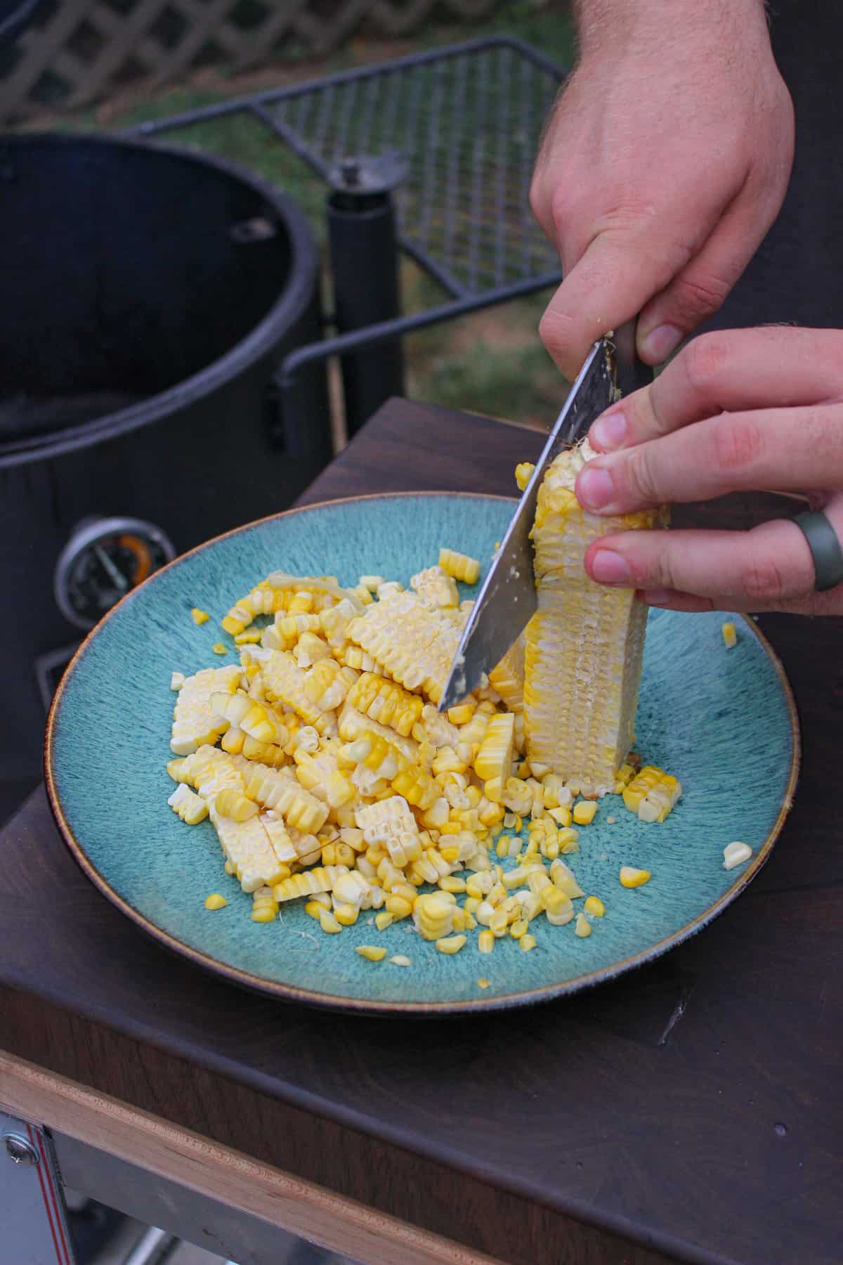 cooked corn being shaved off of the cob