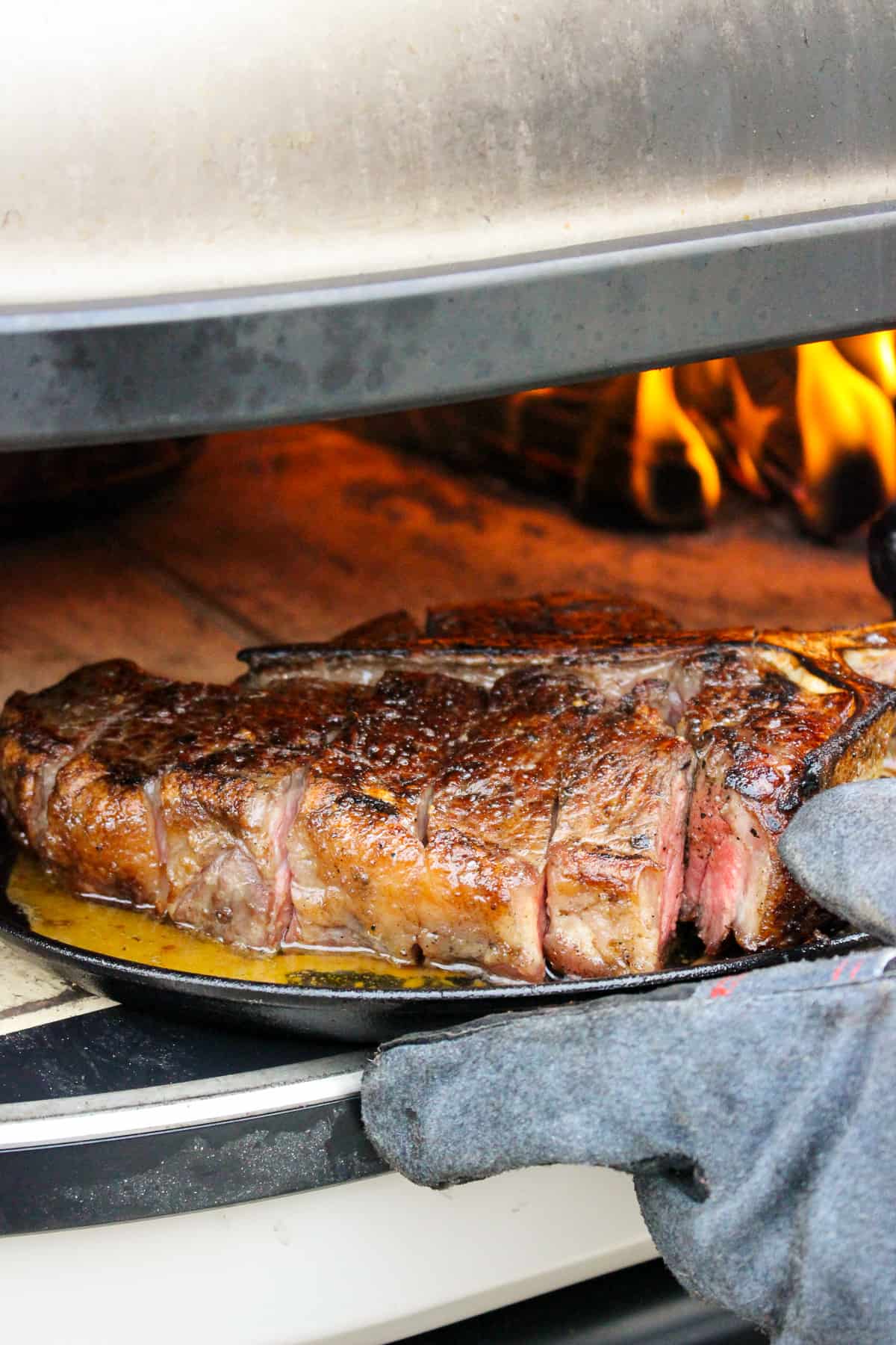 sliced peter luger style steak being placed back into the pizza oven