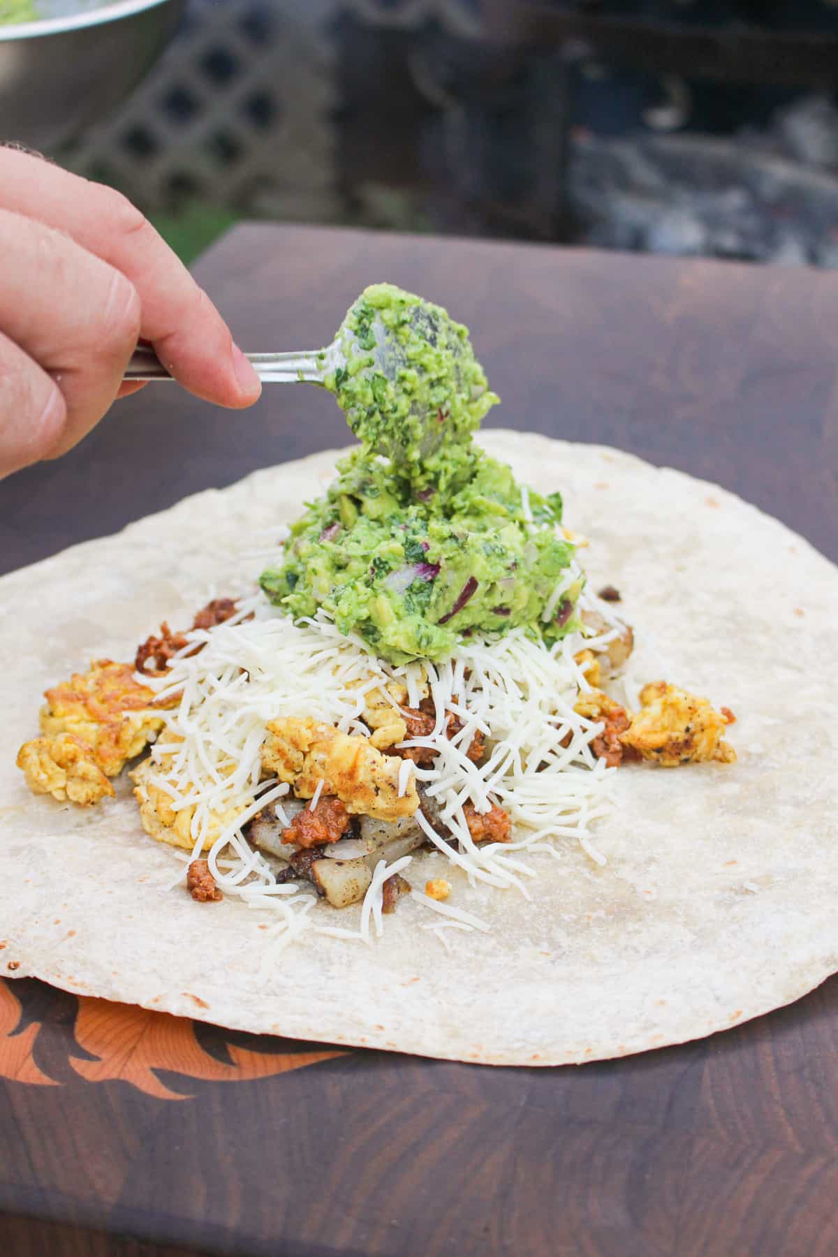 tortilla being topped with burrito fillings