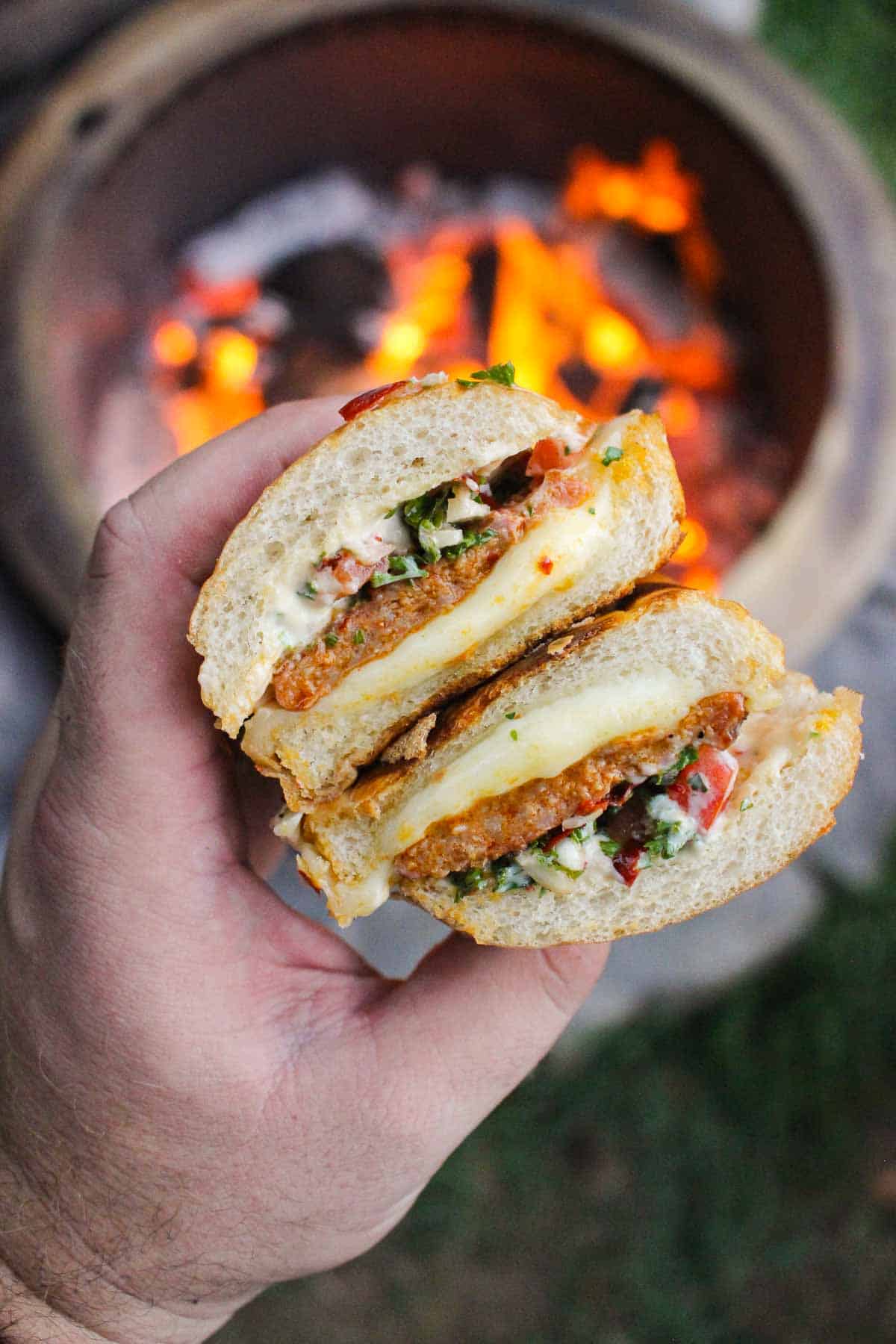 two halves of a cheese stuffed choripan sandwich held over a fire