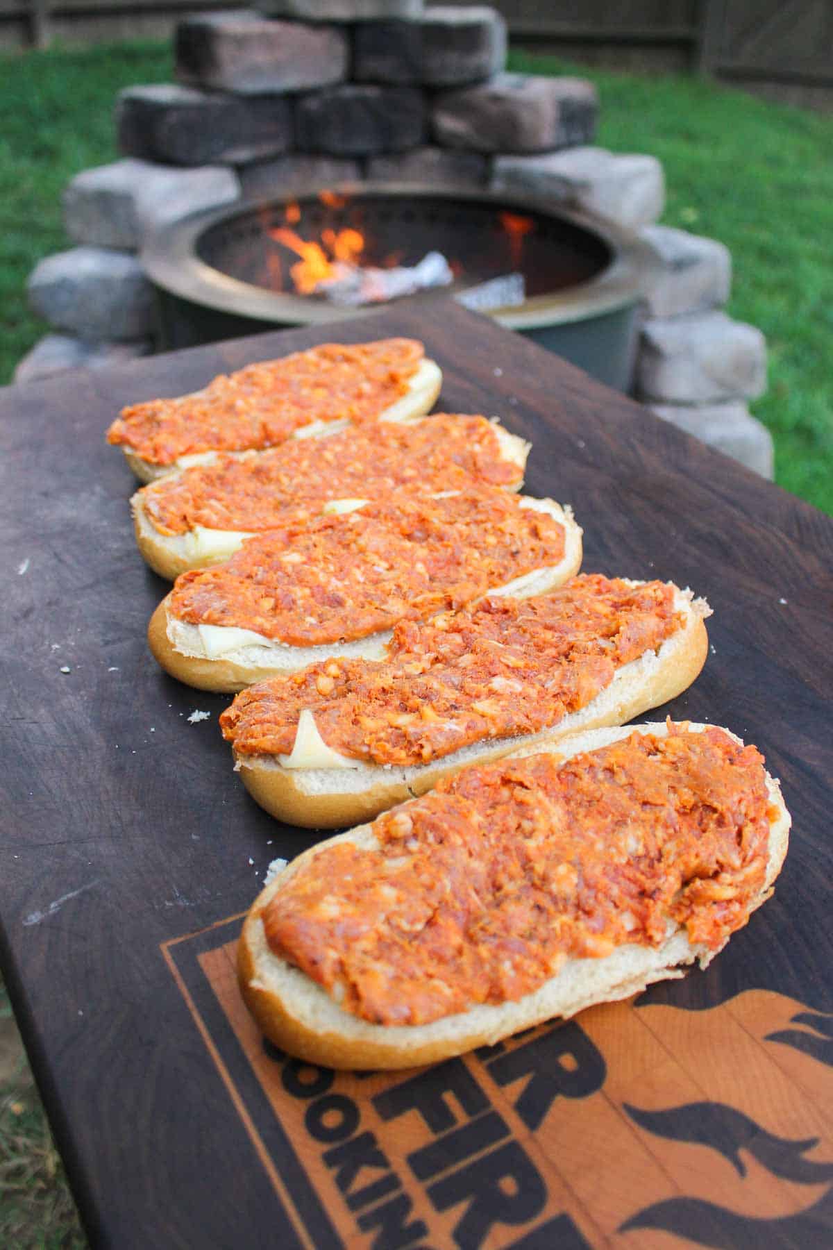 five hoagie rolls covered in chorizo sausage lined on a cutting board